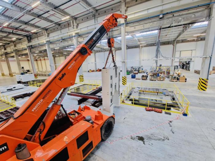 Podnoszenie szafy sterowniczej prasy AIDA podczas instalacji w zakładzie przemysłowym. 