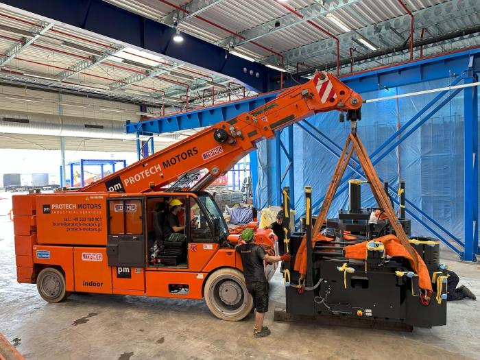 Podnoszenie wtryskarki pasami transportowymi podczas relokacji wewnątrzzakładowej. 