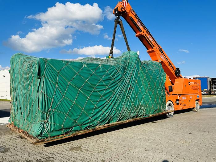 Przemieszczanie wielkogabarytowej wtryskarki na platformie transportowej z użyciem pasów nośnych. 