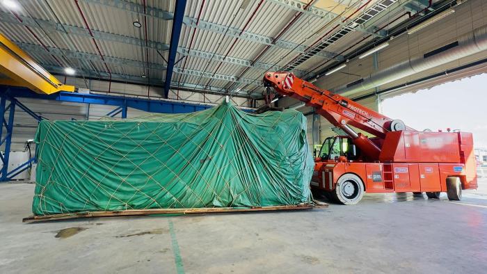 Wprowadzenie wtryskarki do hali produkcyjnej przy użyciu dźwigu przemysłowego. 