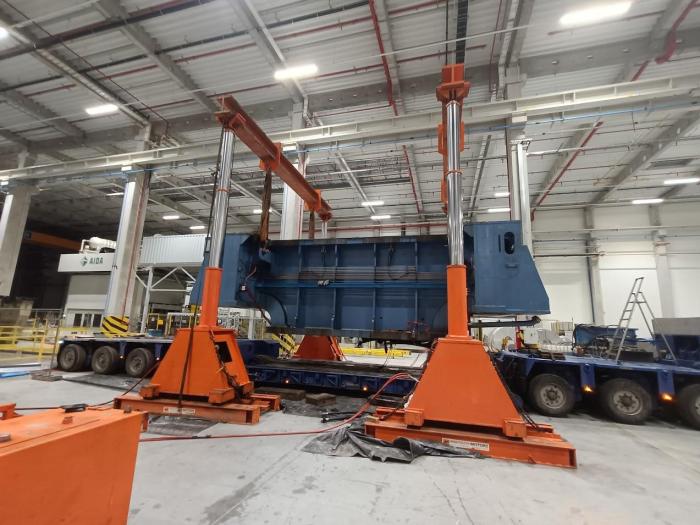 Załadunek ciężkiego elementu prasy przy użyciu hydraulicznej bramownicy podnoszącej. 