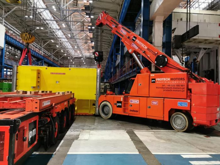 ORMIG 100 IE w trakcie załadunku ciężkiego elementu konstrukcyjnego na platformę transportową. 