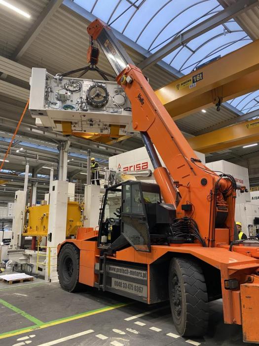 Dźwig przemysłowy VALLA podczas montażu górnego modułu prasy mechanicznej w hali produkcyjnej. 