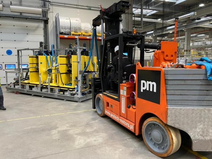 Dźwig MOBILLIFT podczas załadunku ciężkiego urządzenia na naczepę niskopodwoziową. 