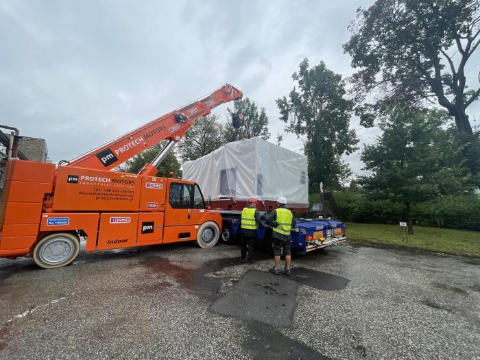 Załadunek obrabiarki do wyrobu śrub przy użyciu żurawia samojezdnego przed transportem. 