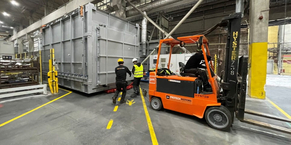 Wózek widłowy podczas przemieszczania ciężkiej konstrukcji stalowej w hali produkcyjnej. 